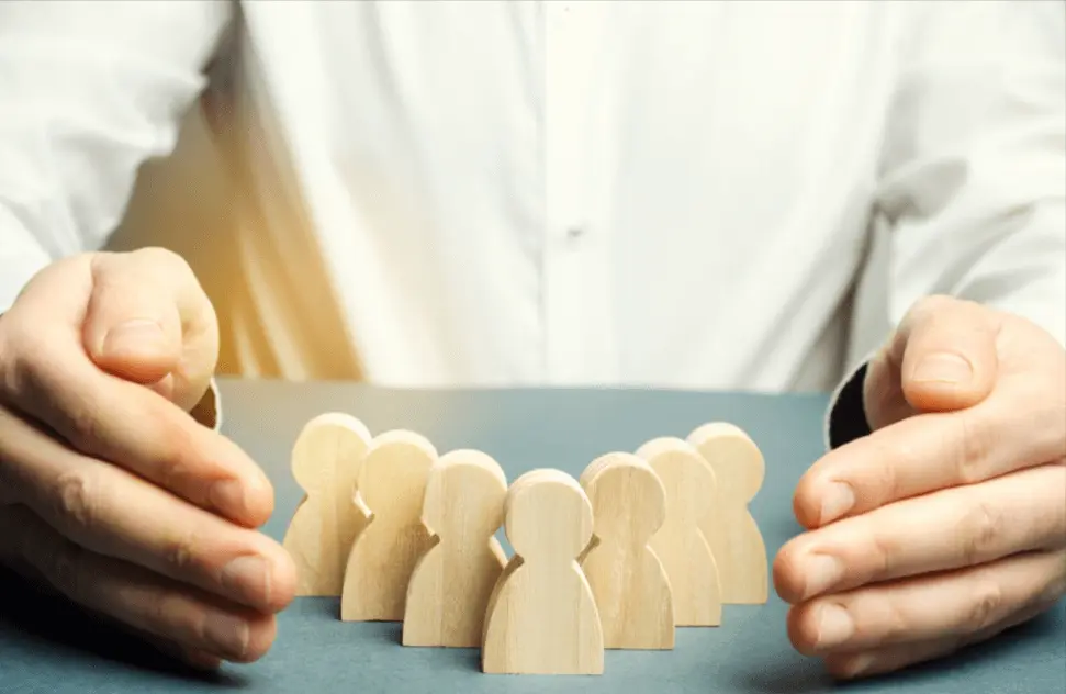 Wooden blocks representing children being protected by an adult's hands