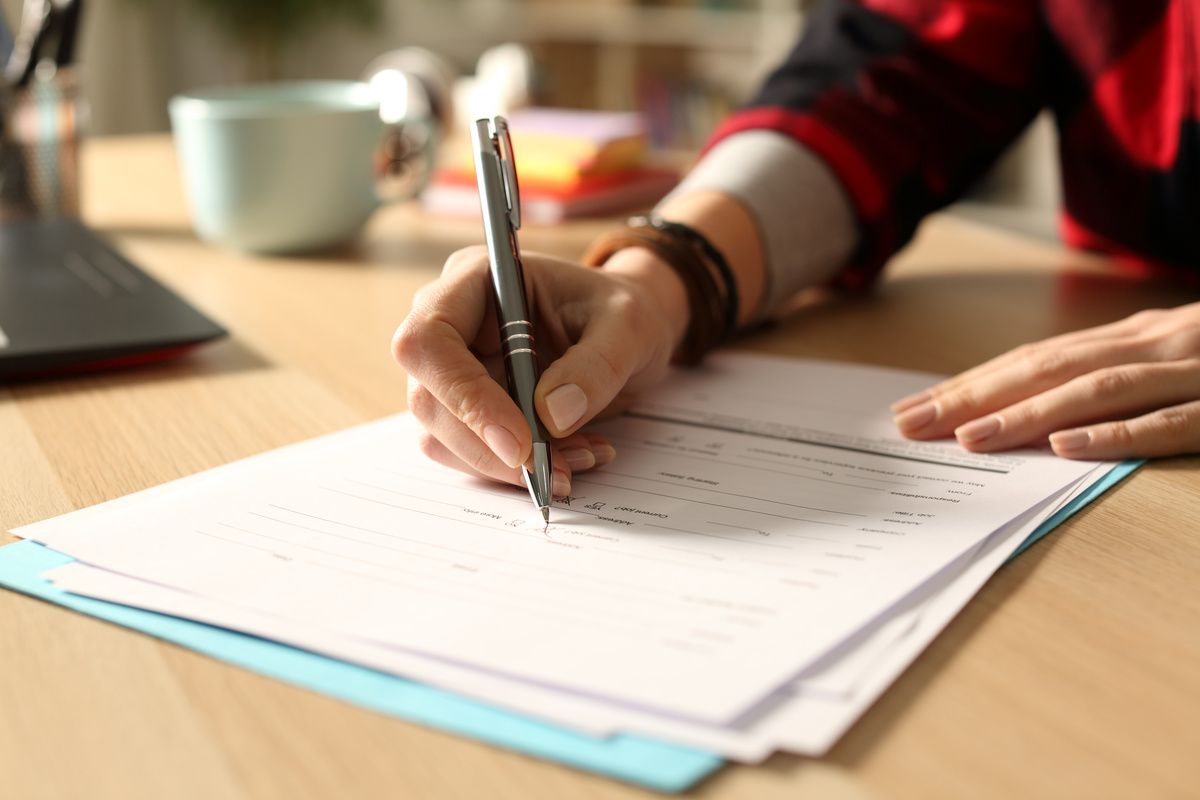 A teacher fills in an accident record form at her desk in a school. 